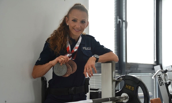 Policjantka prezentuje medale zawieszone na szyi.