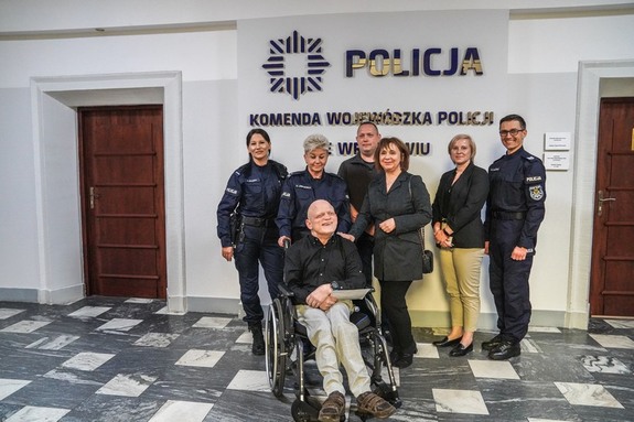 Wspólne zdjęcie Chłopaka na wózku inwalidzkim z policjantami i pracownica cywilną i opiekunami