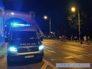 Stojący w okolicy mostu Grunwaldzkiego we Wrocławiu oznakowany radiowóz Policji z włączonymi sygnałami świetlnymi pojazdu uprzywilejowanego