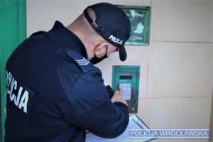 Policjant dzwoniący domofonem podczas sprawdzania osób na kwarantannie